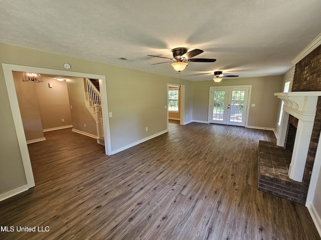 unfurnished living room with dark hardwood / wood-style floors, ceiling fan, a textured ceiling, and a brick fireplace