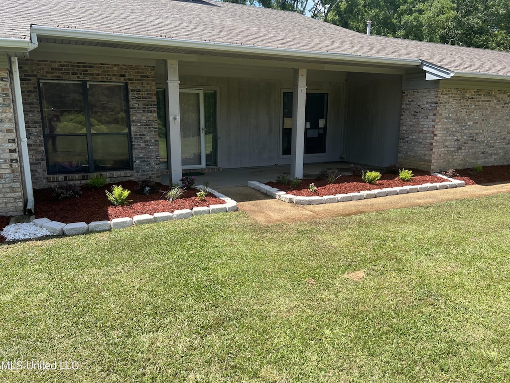 4101 Henderson Rd, Byram, MS 39272 - doorway to property with brick siding, a lawn, a shingled roof, and covered porch