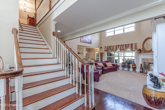 1000 Cedar Hill Rd, Madison, MS 39110 - staircase featuring crown molding, plenty of natural light, a high ceiling, a fireplace, and hardwood / wood-style floors