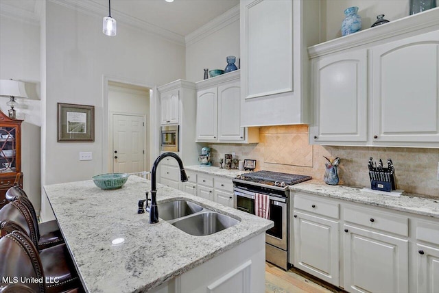 kitchen with appliances with stainless steel finishes, sink, a center island with sink, white cabinetry, and hanging light fixtures