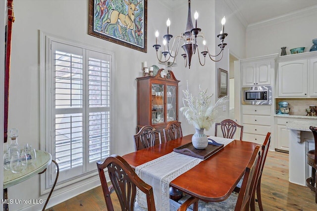 dining room with light wood-type flooring, an inviting chandelier, plenty of natural light, and ornamental molding