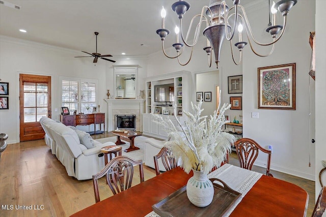 dining room with crown molding, light hardwood / wood-style floors, and ceiling fan with notable chandelier