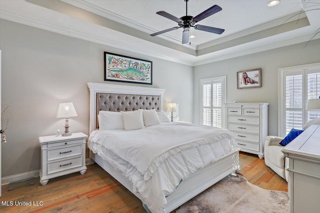 bedroom featuring ceiling fan, a raised ceiling, ornamental molding, and dark wood-type flooring