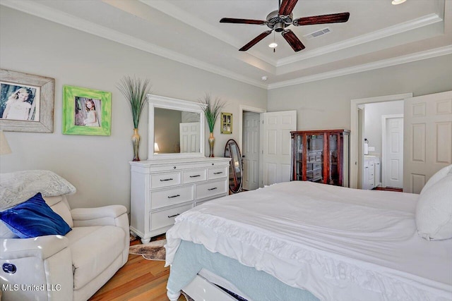 bedroom with a tray ceiling, ceiling fan, light hardwood / wood-style flooring, and ornamental molding