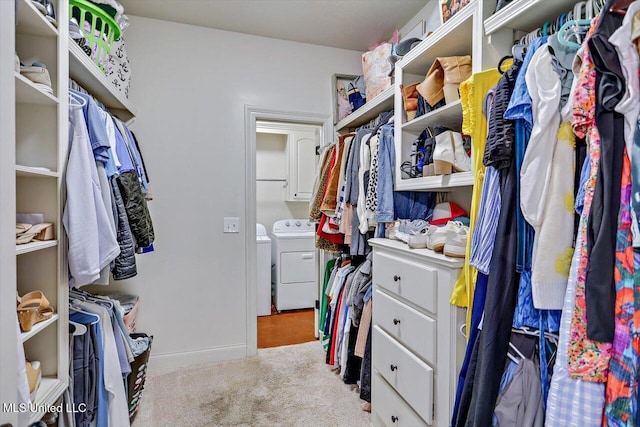 walk in closet featuring washing machine and dryer and light carpet