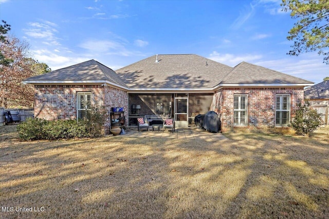 back of property with a sunroom, a patio area, and a yard