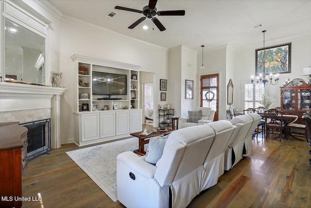 living room featuring a fireplace, dark hardwood / wood-style flooring, ceiling fan with notable chandelier, and ornamental molding