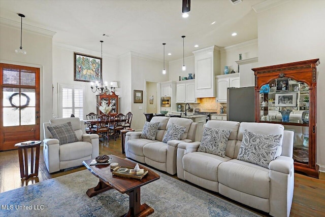 living room featuring a chandelier, dark hardwood / wood-style floors, crown molding, and sink