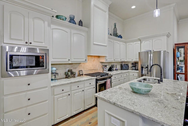 kitchen featuring tasteful backsplash, stainless steel appliances, sink, a center island with sink, and hanging light fixtures