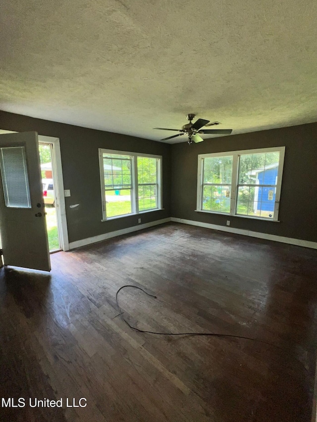 4515 25th St, Meridian, MS 39307 - unfurnished living room with a textured ceiling, baseboards, dark wood-type flooring, healthy amount of natural light, and ceiling fan
