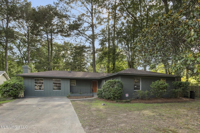 view of front facade with a chimney, board and batten siding, driveway, and a shingled roof