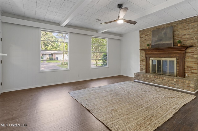unfurnished living room featuring dark wood-style flooring, beamed ceiling, a ceiling fan, a brick fireplace, and baseboards