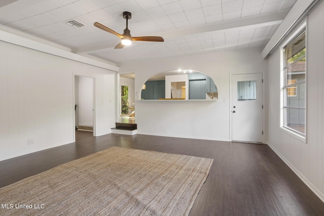 spare room featuring wood finished floors, a ceiling fan, healthy amount of natural light, and beam ceiling