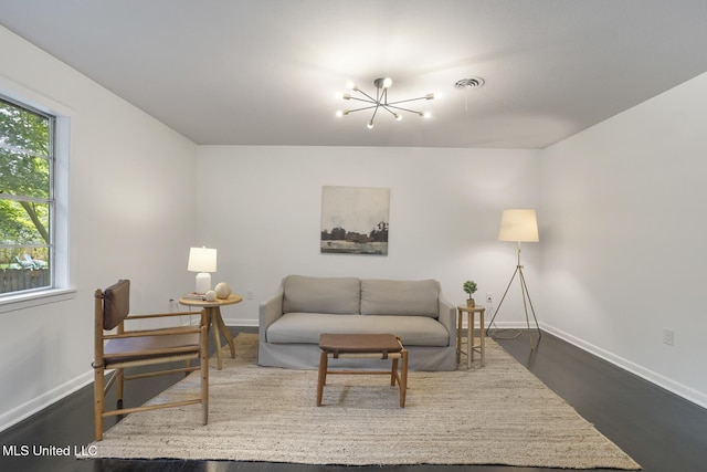 living area with a chandelier, baseboards, and dark wood-type flooring
