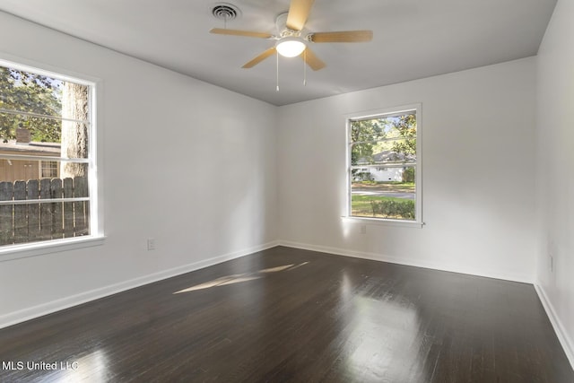 spare room with healthy amount of natural light, ceiling fan, and dark wood-style floors