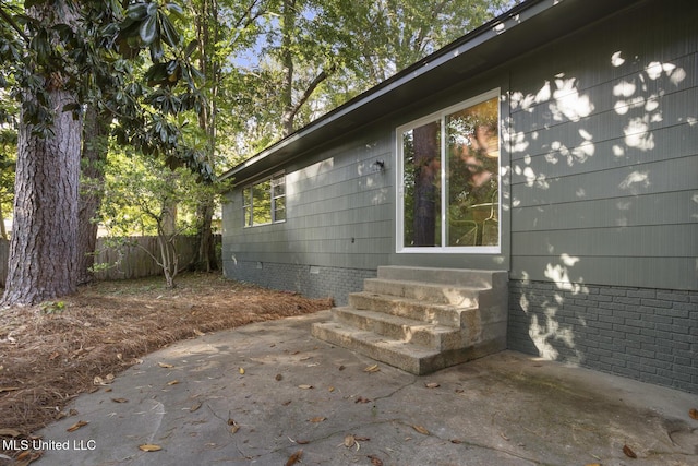 view of property exterior featuring entry steps, a patio, fence, and crawl space
