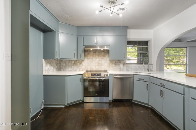kitchen featuring stainless steel appliances, a sink, gray cabinetry, and dark wood-style floors
