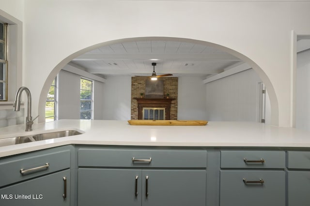 kitchen with beamed ceiling, a sink, wooden ceiling, light countertops, and arched walkways