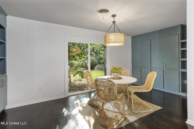 dining area with wood finished floors, baseboards, and a decorative wall