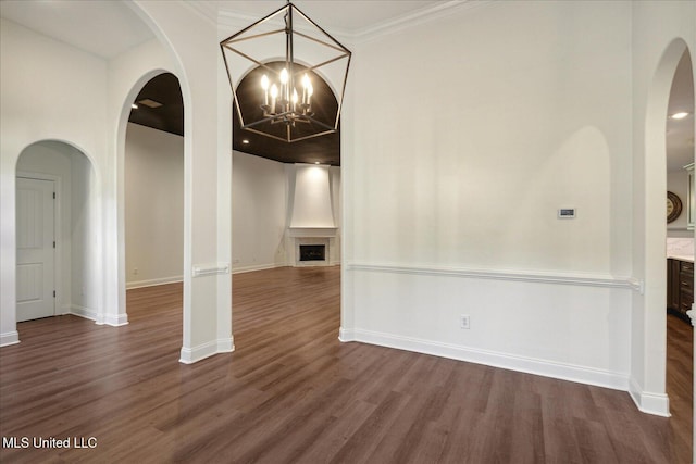 spare room with dark wood-type flooring, ornamental molding, and a chandelier