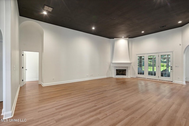 unfurnished living room with a large fireplace, light hardwood / wood-style flooring, and a high ceiling