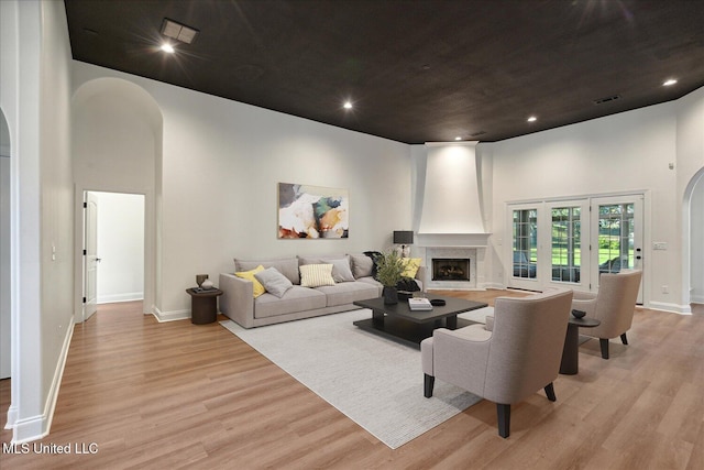 living room with a towering ceiling, light hardwood / wood-style floors, and a large fireplace