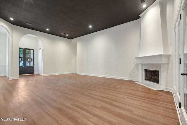 unfurnished living room featuring french doors, a high end fireplace, and light hardwood / wood-style floors