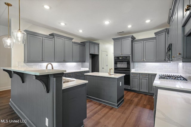 kitchen with gray cabinets, a kitchen island, pendant lighting, and black appliances