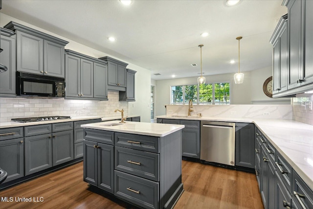 kitchen with appliances with stainless steel finishes, gray cabinets, sink, and hanging light fixtures