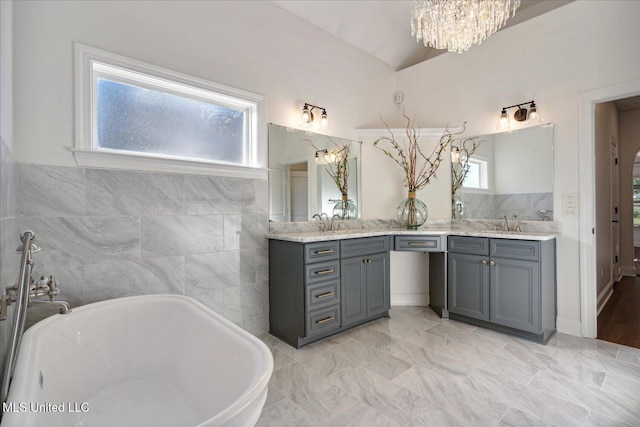 bathroom featuring a washtub, vanity, a wealth of natural light, and vaulted ceiling