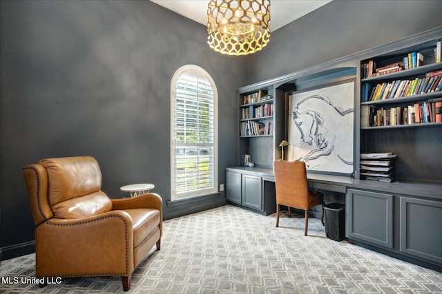 carpeted office with a notable chandelier and built in desk