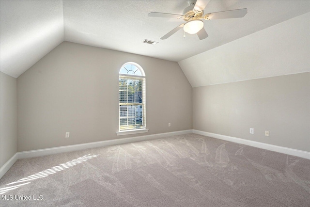 additional living space with a textured ceiling, carpet floors, ceiling fan, and vaulted ceiling