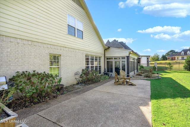 rear view of house with a sunroom, a yard, and a patio