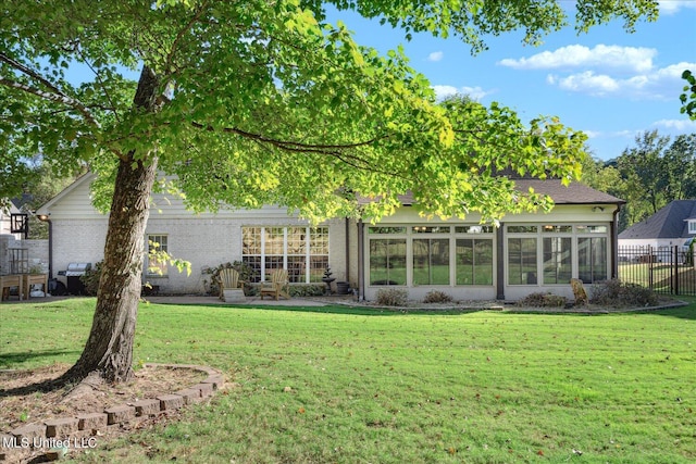 back of house with a sunroom and a lawn