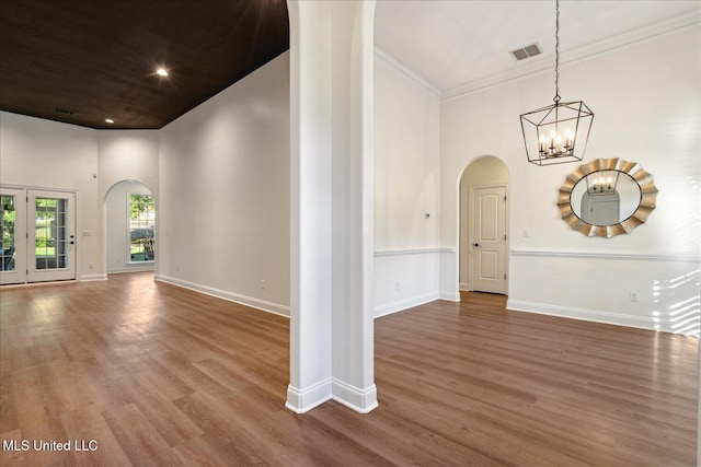 interior space featuring hardwood / wood-style flooring, ornamental molding, a towering ceiling, and an inviting chandelier