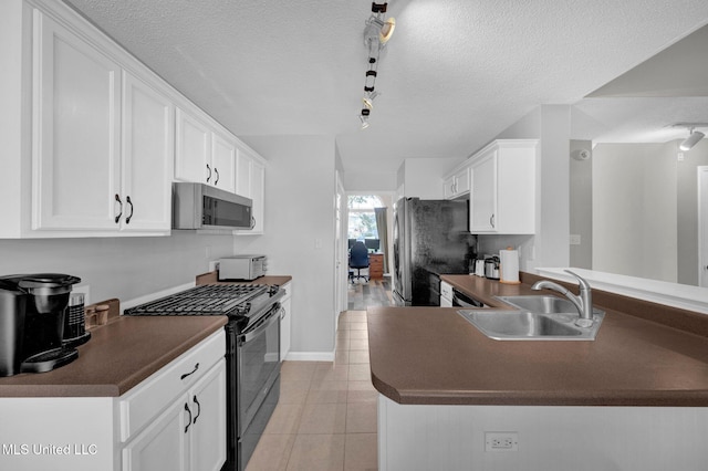 8968 Tahoe Cv, Olive Branch, MS 38654 - kitchen with appliances with stainless steel finishes, dark countertops, rail lighting, white cabinetry, and a textured ceiling