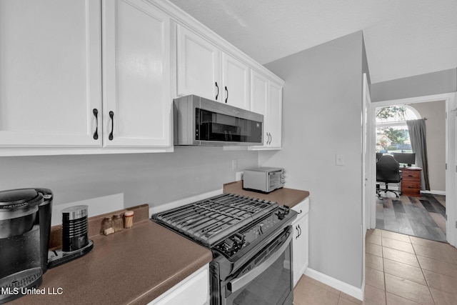 8968 Tahoe Cv, Olive Branch, MS 38654 - kitchen featuring stainless steel microwave, black range with gas stovetop, white cabinets, light tile patterned floors, and dark countertops
