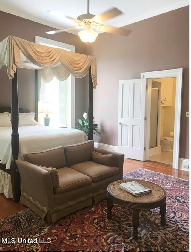 bedroom featuring hardwood / wood-style floors, ceiling fan, and ensuite bath