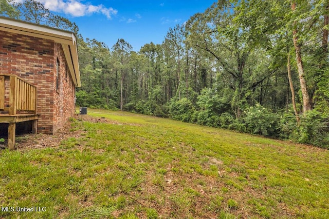 29 Summer Ln, Poplarville, MS 39470 - view of green lawn featuring a view of trees, central air condition unit, and a deck