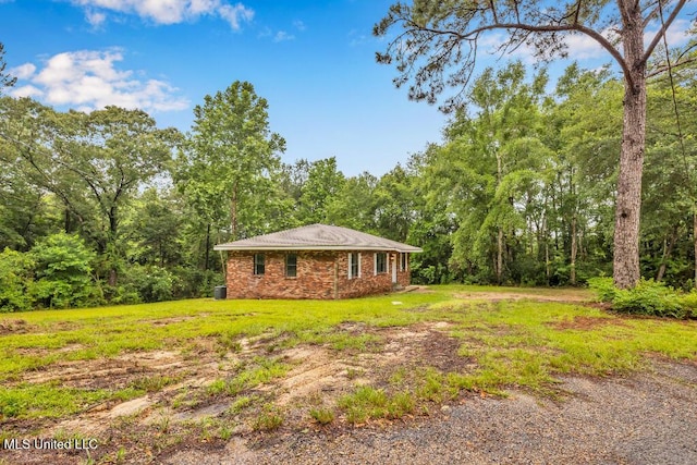29 Summer Ln, Poplarville, MS 39470 - view of home's exterior with brick siding, a wooded view, and a yard