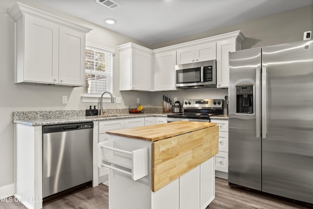 kitchen featuring butcher block counters, sink, white cabinetry, a center island, and appliances with stainless steel finishes