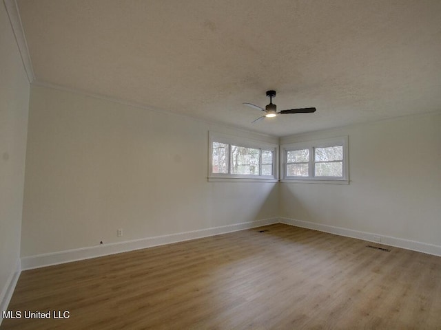 empty room featuring visible vents, a textured ceiling, baseboards, and wood finished floors