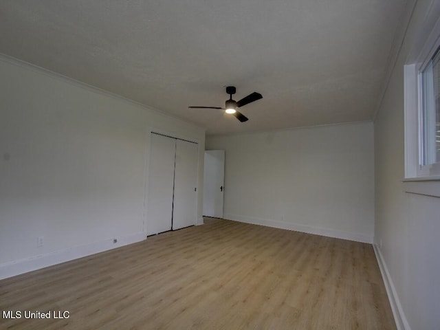 unfurnished bedroom featuring a closet, ornamental molding, ceiling fan, wood finished floors, and baseboards