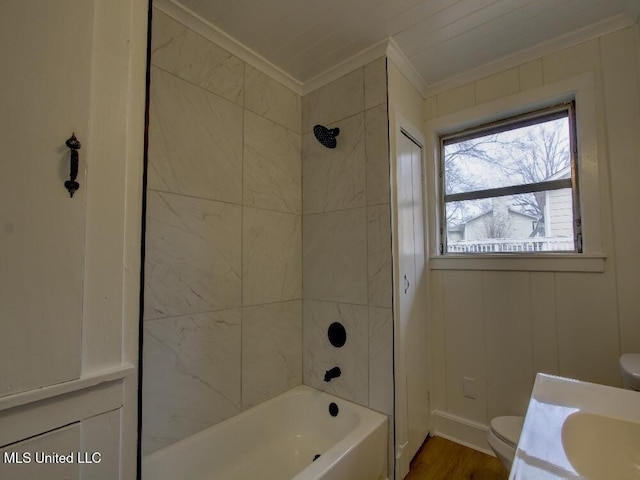 bathroom with toilet, wood finished floors, vanity, ornamental molding, and washtub / shower combination