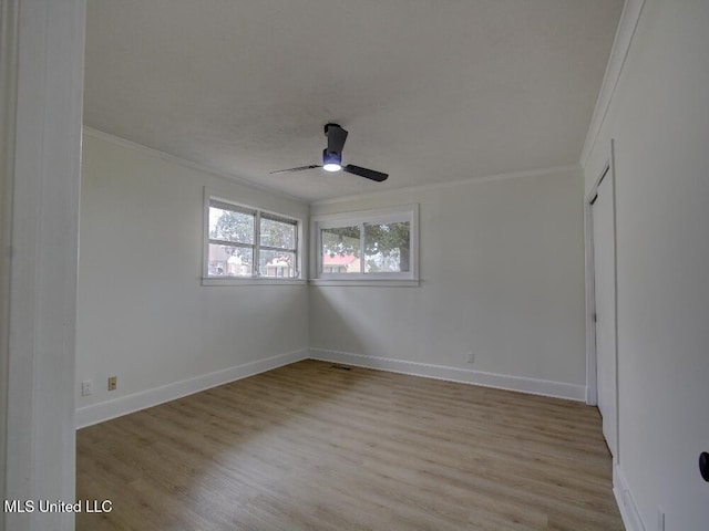 empty room with ornamental molding, wood finished floors, and baseboards