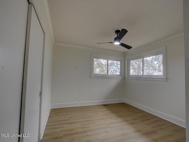 empty room featuring baseboards, ceiling fan, light wood-type flooring, and crown molding