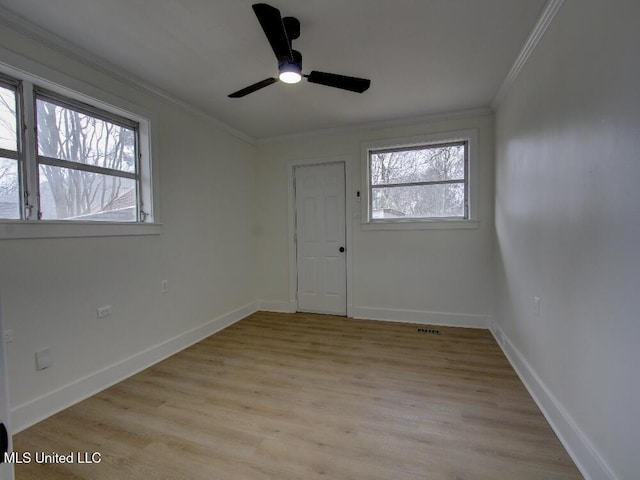 empty room with light wood finished floors, baseboards, and crown molding