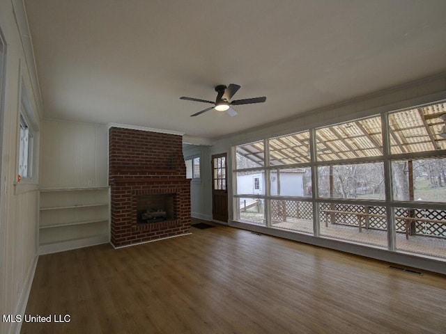 unfurnished living room featuring ornamental molding, a fireplace, wood finished floors, and visible vents