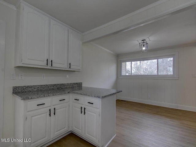 kitchen featuring baseboards, wood finished floors, white cabinets, and light stone countertops