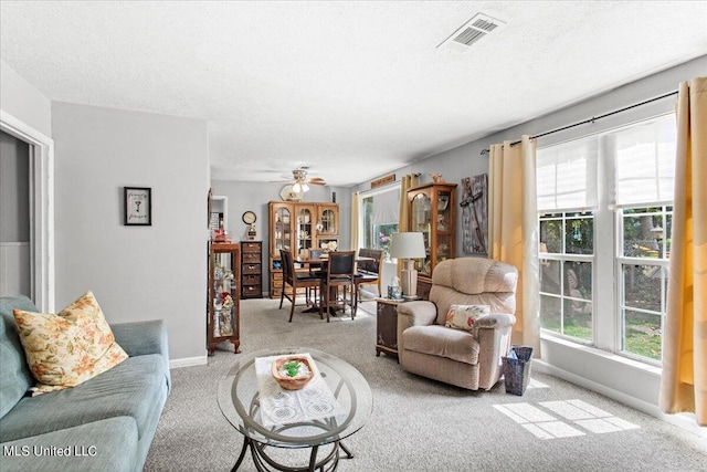 living room featuring a wealth of natural light, a textured ceiling, light colored carpet, and ceiling fan